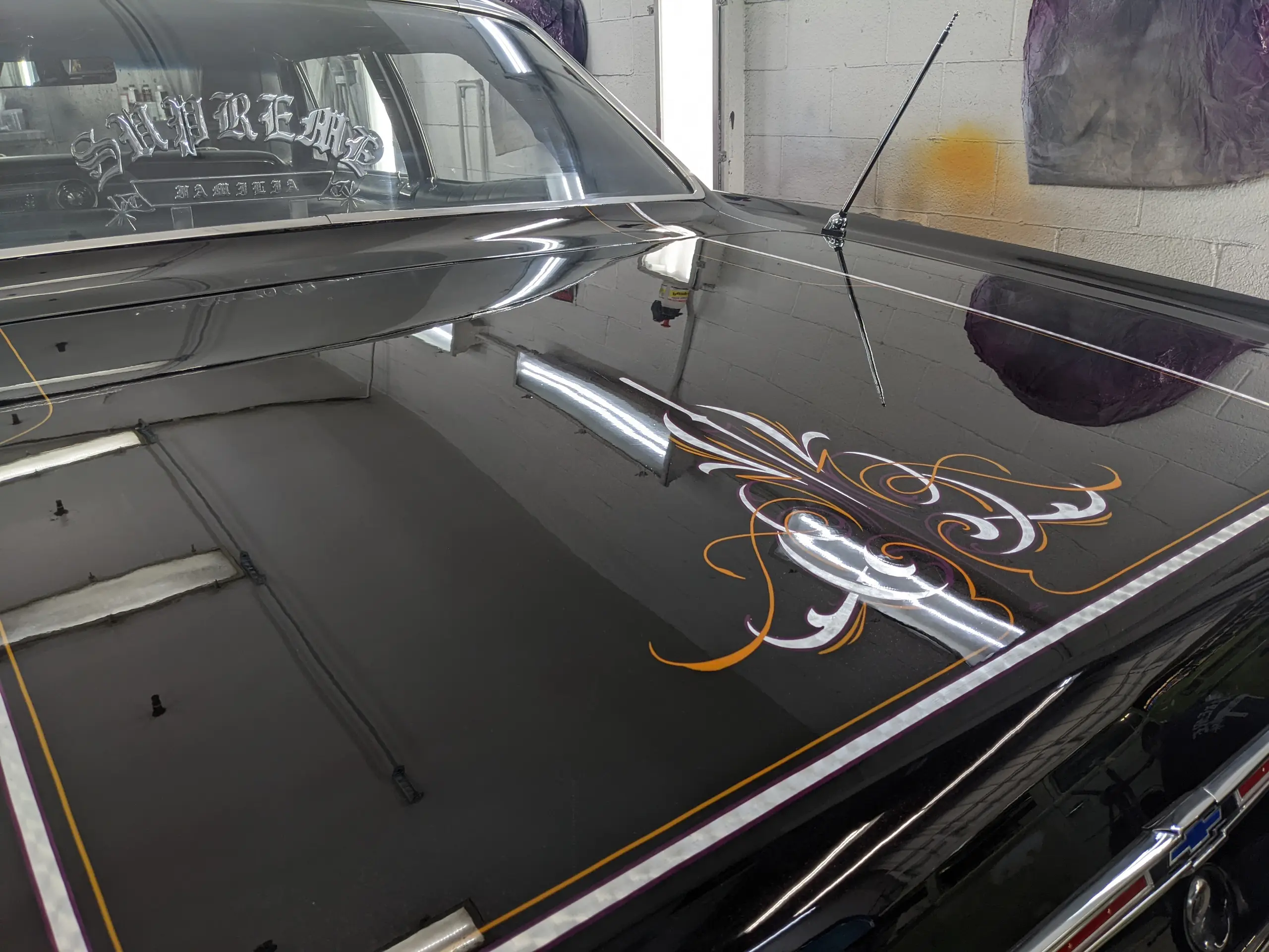 Filet peint à la main sur le capot noir d’une Chevrolet Impala, la lumière révélant la ligne